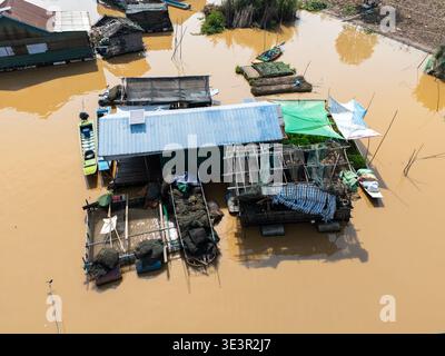 Aus dem schlammigen Wasser erheben sich die Stelzenhäuser aus der Vogelperspektive und spiegeln den Himmel wider, ein Zeugnis für das Leben, das dem Rhythmus von Tonle SAP in Kambodscha angepasst ist. Stockfoto