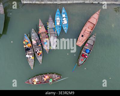Aus der Vogelperspektive sehen Sie farbenfrohe Boote, die sich dicht auf dem stillen, jadegrünen Wasser des Flusses Hoi an, Vietnam, ansammeln. Stockfoto