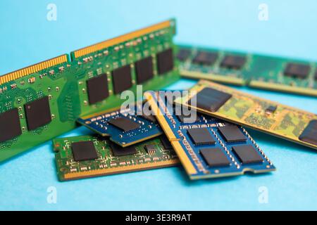 Computerspeichermodule verschiedener Typen sind auf einer blauen Tabelle mit Mikrochips und farbigen Schaltungsdesigns angeordnet. Stockfoto