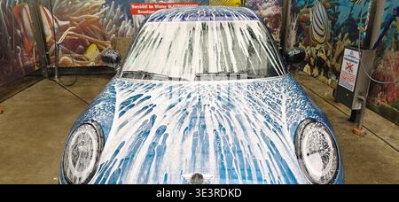 Berlin, Deutschland - 18. Mai 2025: Blaues Fahrzeug wird an der Waschanlage mit Seifenschaum bedeckt. Stockfoto