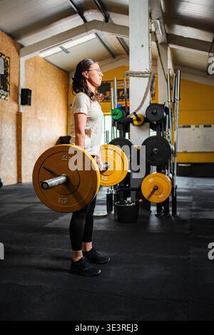 Frau, die mit Langhantel steht, nachdem sie Gewichte gehoben hat Stockfoto
