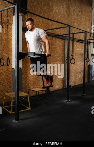 Ein Mann, der in einem Fitnessstudio Dips an parallelen Gittern durchführt Stockfoto
