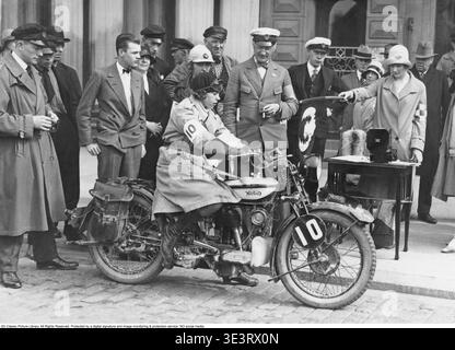 Frau auf einem Motorrad, Juni 1929. Der Beginn eines Motorradrennens. Eine Beamtin, die einen typischen Hut aus den 1920er Jahren trägt, hält die Startfahne bereit. Vor ihr steht eine große Stoppuhr. Eine kleine Menge neugieriger Zuschauer hat sich auf der Straße in Stockholm versammelt. Die Hauptfigur ist Greta Gustafsson, die auf ihrem Norton-Motorrad sitzt. Zu dieser Zeit war es für Frauen nicht ungewöhnlich, an Motorrennen teilzunehmen. Stockfoto