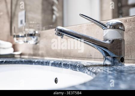 Moderner Chrom-Wasserhahn auf luxuriösem blauem Marmorwaschbecken mit weichem Hintergrund. Nahaufnahme, geringe Schärfentiefe Stockfoto