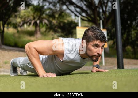 Junger Mann, der Liegestützen im Park draußen trainiert Stockfoto