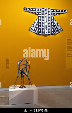 Zeitgenössische Denim-Chapan-Textilcollage mit kasachischem Text und abstrakter Metallskulptur in der Galerie des Almaty Museum of Arts Stockfoto