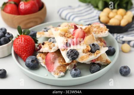 Leckere Joghurtrinde mit Beeren und Müsli auf dem Lichttisch, Nahaufnahme Stockfoto