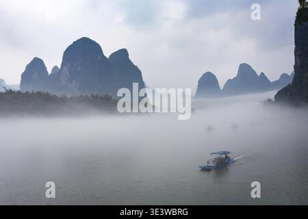 Reise nach China mit Schiffen auf dem Fluss in der Nähe der Stadt Xingping im Yangshuo County am Frühlingsmorgen Stockfoto