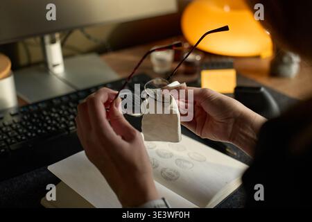 Frau putzt Brille mit Tuch über offenem Notebook am Schreibtisch Stockfoto