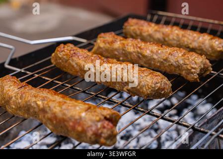 Nahaufnahme von frisch gegrillten Kofta-Kebabs auf einem Holzkohlegrill. Die Spieße bieten eine perfekte Mischung aus Gewürzen und Kräutern, die einen köstlichen Stockfoto