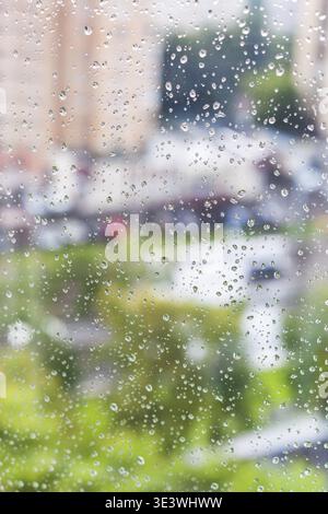 Regentropfen auf dem Fenster und verschwommenes Stadtbild im Hintergrund Stockfoto
