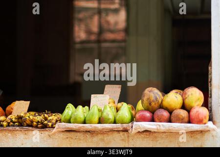 Eine Vielzahl von tropischen Früchten, einschließlich Mangos, Bananen und Avocados, ausgestellt auf einem rustikalen Marktstand in La Havana, Kuba. Die Einstellung erfasst die Stockfoto