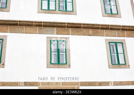 Nahaufnahme der weißen Fassade des Leuchtturms Cape Finisterre in Galicien, Spanien, mit grün gerahmten Fenstern und Steinakzenten, die die Küste hervorheben Stockfoto