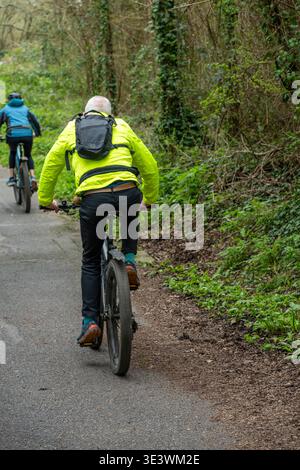 Ältere oder ältere Ehepaare, die auf der isle of wight, Großbritannien, auf einer Landstrecke mit dem Fahrrad fahren Stockfoto