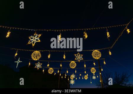 Gemütliche Winternächteszene mit festlichen Lichtern, die das Dorf erleuchten. Stockfoto