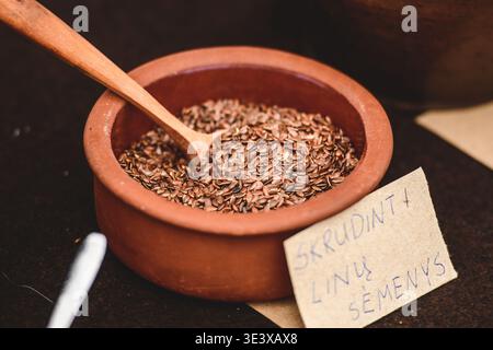 Leinsamen, auch als Leinsamen bekannt, in einer Terrakotta-Schüssel mit einem Holzlöffel Stockfoto