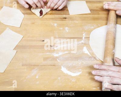 Frau rollt Teig mit Nudel für Fleischknödel auf einem Holztisch aus Stockfoto
