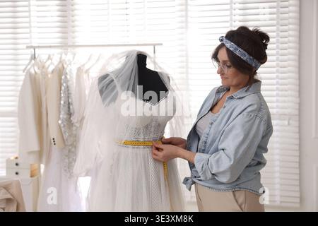 Schneiderin bei der Messung von Hochzeitskleidern im Atelier Stockfoto
