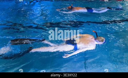 Zwei Schwimmer trainieren mit Flossen und Schnorcheln in einem Innenpool Stockfoto