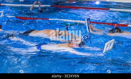 Schwimmer trainieren mit Schnorcheln in einem Pool, wobei sie konstante und konzentrierte Bewegungen beibehalten. Stockfoto