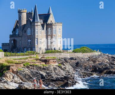 Das historische Turpault Mansion, eine neogotische Burg, überblickt die zerklüftete Küste der Cote Sauvage in Quiberon, Bretagne, Frankreich, wo sich die Menschen entspannen Stockfoto