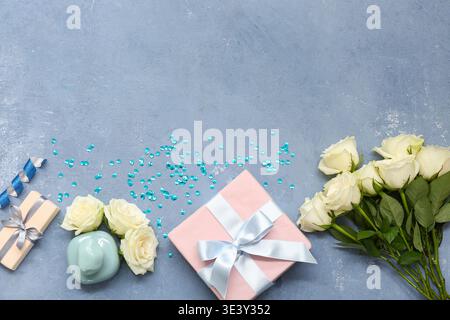 Komposition mit Geschenkbox, weißen Rosenblüten und Flasche Parfüm auf blauem Grunge-Hintergrund Stockfoto