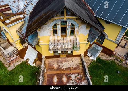 Verlassenes, reich verziertes Herrenhaus von oben. Die verfallene Fassade, der zerbröckelnde Balkon und das verwitterte Dach betonen architektonische Pracht und Vernachlässigung. Turliki, Obn Stockfoto