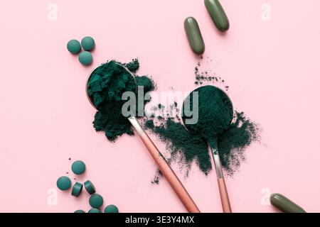 Löffel mit Spirulina Kapseln, Tabletten und Pulver auf rosa Hintergrund Stockfoto