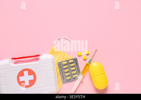 Erste-Hilfe-Set mit Pillen, medizinischer Maske und Spritze auf rosa Hintergrund Stockfoto