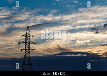 Die Silhouette des Sendeturms bildet einen starken Kontrast zu einem dramatischen, farbenfrohen Himmel im Frühlingsuntergang, der mit schroffen Wolken und dunklen Unterschichten gefüllt ist Stockfoto