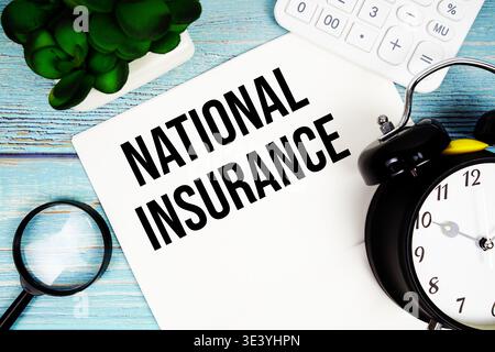 National Insurance auf Papier geschrieben, auf einer blauen Holzoberfläche, neben einer Lupe, einer Uhr, einem Taschenrechner und einer kleinen Pflanze Stockfoto