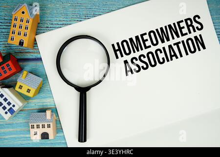 Notizblock mit 'HOA Homeowner Association' mit Lupe und Hausmodell auf hölzernem Hintergrund Stockfoto