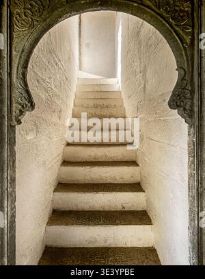 Eine Reihe von Stufen in einer Treppe führt zu einer Landung mit Licht durch eine Tür, die wie ein Schlüsselloch geformt ist. Stockfoto