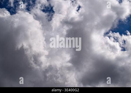 Dramatischer Himmel voller flauschiger weißer Wolken gegen tiefblaues Blau. Dunkle Sturmwolken deuten auf wechselhaftes Wetter hin. Perfekt für spannende Hintergründe, n Stockfoto