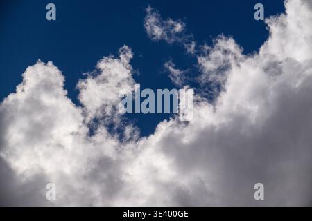 Weiße, flauschige Wolken ziehen über den tiefblauen Himmel. Wolken haben weiche Kanten und strukturierte Schatten. Das Bild zeigt eine friedliche Himmelsszene. Perfekt für das Wetter, Trav Stockfoto