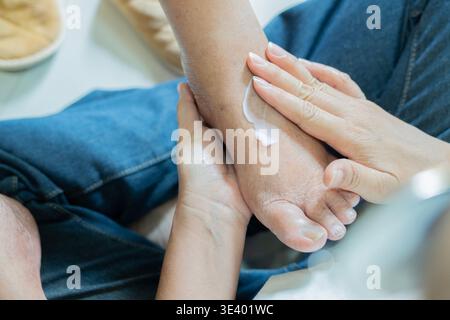 Pflege für ältere Menschen mit Feuchtigkeitscreme auf die Haut aufgetragen, sanfte Hände für Entspannung und Komfort. Fußpflegeroutine fördert das Wohlbefinden Stockfoto