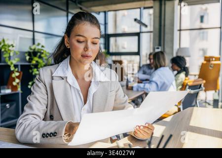 Fokussierte Analyse Von Diagrammen Für Frauen. Frau, Die Die Gedruckten Daten Und Diagramme Sorgfältig Überprüft Stockfoto