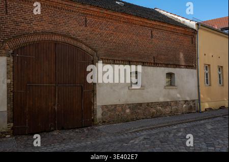Historisches Stein- und Backsteingebäude mit Holzbogentor Stockfoto