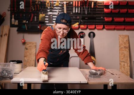 Holzarbeiter, der Farbe auf Holzbretter aufträgt. Der Zimmermann arbeitet in seiner Tischlerei. Kopierbereich Stockfoto