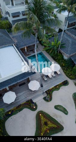 Blick aus der Vogelperspektive auf ein luxuriöses Resort mit Swimmingpool, Palmen und Strohdächern in Siargao, Philippinen. Stockfoto
