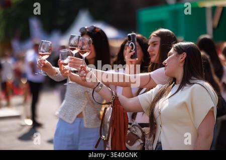 Die Besucher der Yerevan Wine Days erheben gemeinsam Gläser Roséwein, während sie während der Feierlichkeiten im Freien in Jerewan, Armenien, für ein Foto posieren. Stockfoto