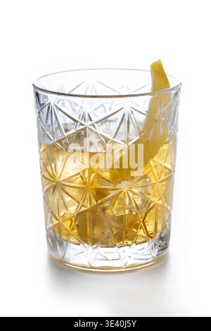 Rostiger Nagelcocktail mit Zitronenschale in Kristallglas isoliert auf weißem Hintergrund Stockfoto
