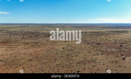 Die weite, trockene Landschaft erstreckt sich bis zum Horizont unter einem klaren blauen Himmel und zeigt die krasse Schönheit der Wüste, Karoo Desert, Nort Stockfoto