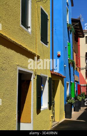 Eine malerische enge Straße mit lebhaften, farbenfrohen Gebäuden mit traditionellen Fenstern und Fensterläden unter einem klaren blauen Himmel, die an ein bezauberndes europäisches Reiseziel erinnern. Stockfoto