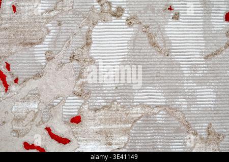 Nahaufnahme mit gemustertem Teppich in Beigetönen, erhöhten Texturen und roten Akzenten, die ein dynamisches abstraktes Design schaffen. Stockfoto