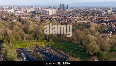 Hochwinkelperspektive auf das Buile Hill Mansion und die Tennisplätze in Salford mit Blick auf die dichte Skyline des Stadtzentrums von Manchester. Stockfoto