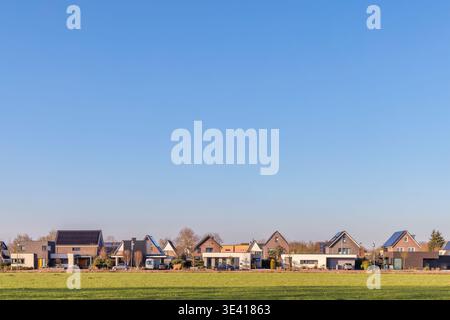 Eine Reihe von luxuriösen niederländischen Häusern vor einer sonnigen Graswiese Stockfoto