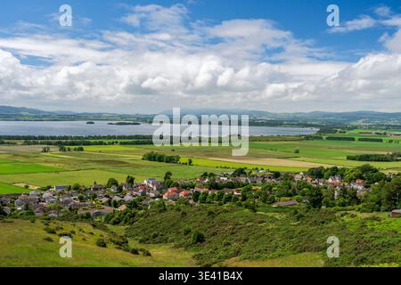 Panoramablick auf Kinesswood Village und Loch Leven in der Nähe von Scotlandwell, mit Flickenteppich-Ackerland, sanften grünen Hügeln, Inseln am Ufer, verstreut Stockfoto