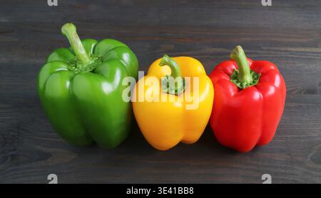 Lebendige Trikolore von Bell Peppers auf schwarzem Holzhintergrund Stockfoto