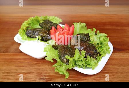 Eine Platte mit Traubenblättern, genannt Dolma (Tolma), mit Joghurt-Dip Stockfoto